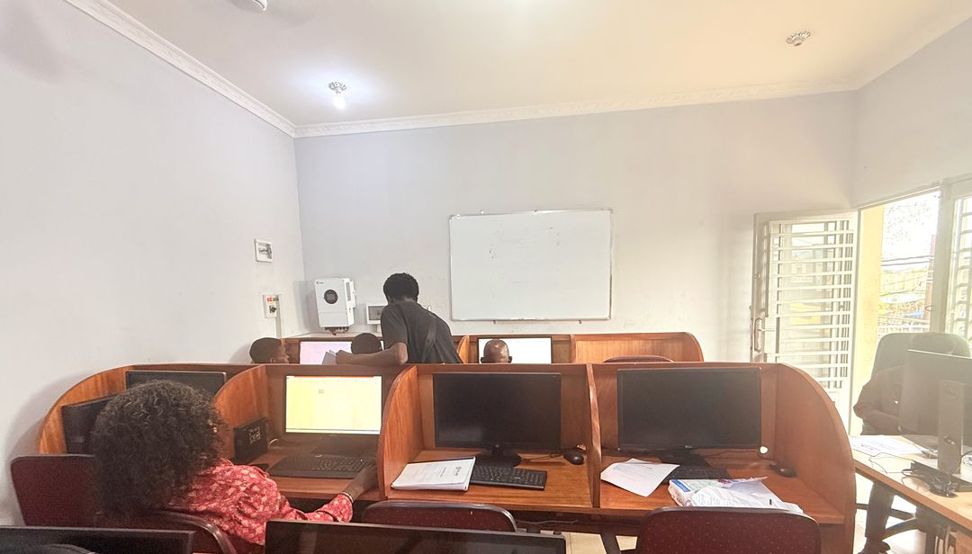 Vue d’ensemble de la salle de formation : postes en bois, tableau blanc, apprenants au travail.